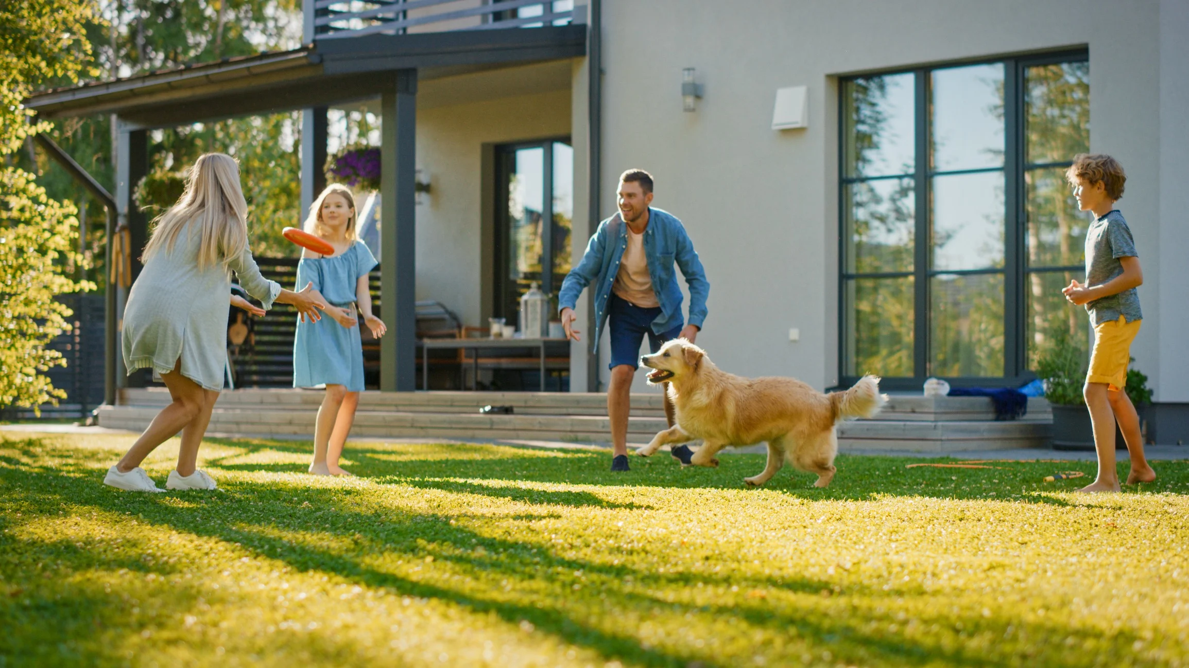 family playing with golden retriever backyard